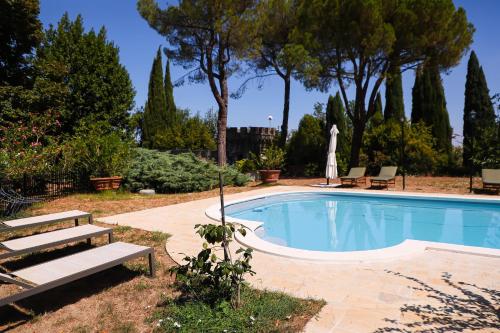 een zwembad in een tuin met banken en bomen bij B&B Castello Machiavelli in Ozzano dell Emilia