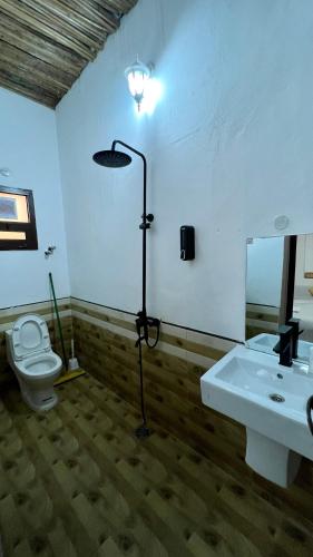 a bathroom with a sink and a toilet and a lamp at Wadi Shab Beach House in Ramlah