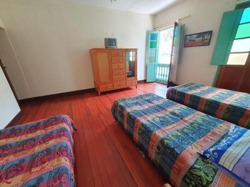 a room with two beds and a wooden floor at Hostal la Casa del Músico in El Cocuy