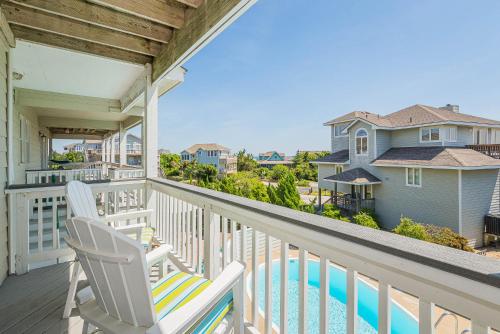a balcony with two chairs and a swimming pool at Simple Gifts by the Sea in Duck