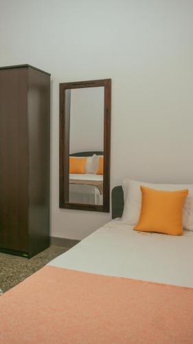 a bed with an orange pillow and a mirror at Kothmale Homestay in Mawatura