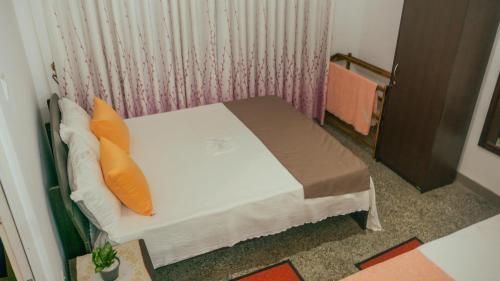 1 cama pequeña con almohadas de color naranja en una habitación en Kothmale Homestay, en Mawatura