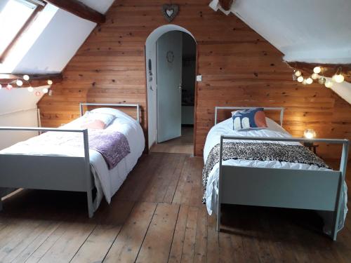 two beds in a room with wooden walls at Maison chaleureuse avec cheminée des coudrais 