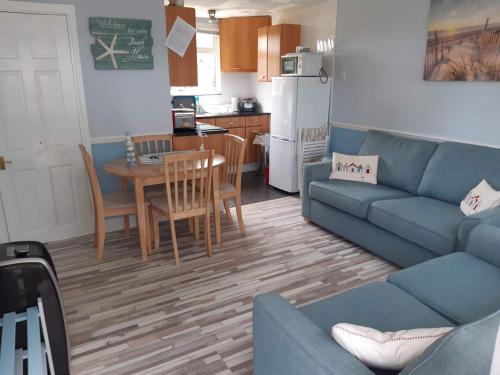 a living room with a couch and a table and a kitchen at Holiday at Hemsby in Hemsby