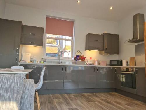 a kitchen with gray cabinets and a table and a window at The Old Warehouse. Warehouse Conversion in quiet central location 2 bed. in Great Yarmouth