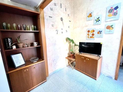 Habitación con TV y pared con reloj. en ROMUhouse economy apartment METRO B en Roma