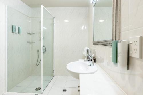 a white bathroom with a shower and a sink at The Glebe Apartments in Queenstown