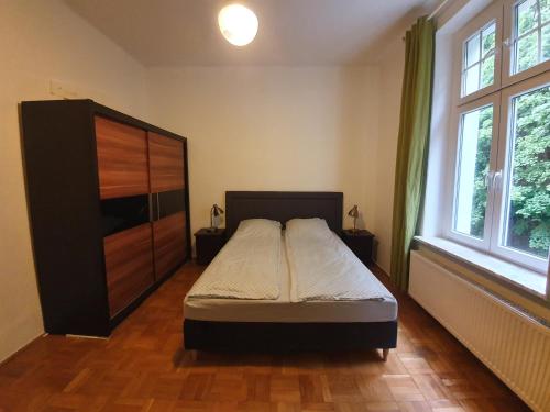 ソポトにあるApartament w centrum Sopotuのベッドルーム1室(ベッド1台付)、大きな木製キャビネットが備わります。
