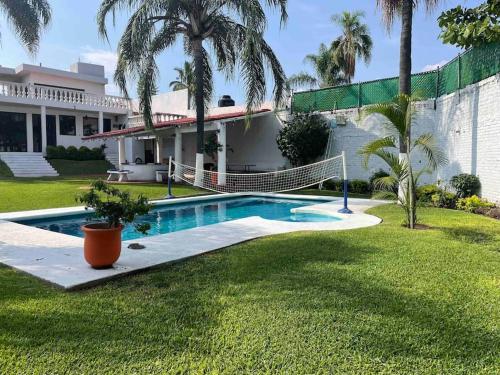 una piscina di fronte a una casa con palme di Casa para fines de semana a Cuernavaca