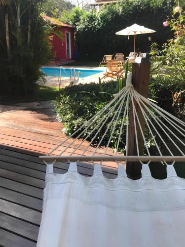 a wooden deck with an umbrella next to a pool at Pousada Jardim do Éden in Serra do Cipo