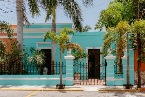 a blue building with palm trees in front of it at Casa Dos Lirios Hotel Boutique in Mérida