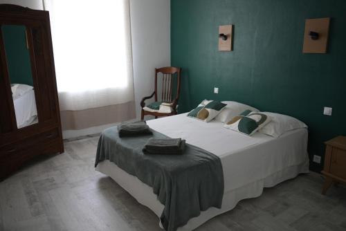 a bedroom with a large bed with a green wall at Le Céles'Thym - SPA Privatif in Conques-sur-Orbiel