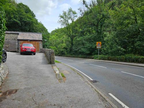 a red car parked on the side of a road at Rose Cottage - Cosy cottage in Millers Dale in Buxton