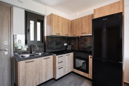 Una cocina con gabinetes de madera y un refrigerador negro. en Blue Icons Lefkas, en Nikiana