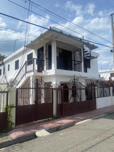 a white house with a gate and a fence at Apartment city center and cable car in San Felipe de Puerto Plata