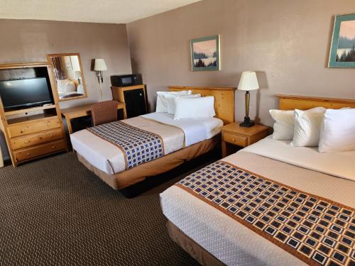 a hotel room with two beds and a flat screen tv at Satellite Inn in Alamogordo