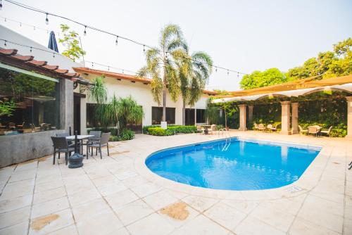 a swimming pool in a patio with a table and chairs at Hotel Los Portales in Chinandega