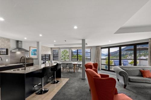 an open kitchen and living room with red chairs at The Glebe Apartments in Queenstown
