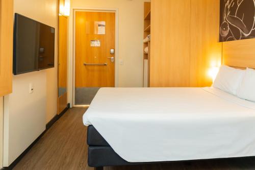 a room with a bed and a flat screen tv at Ibis Porto Alegre Assis Brasil in Porto Alegre