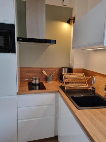 une cuisine avec des armoires blanches et un évier dans l'établissement maison de pêcheur, à Tréffiagat