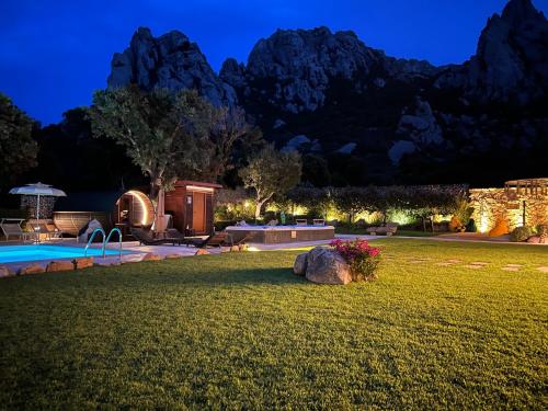 une arrière-cour avec une piscine et des montagnes en arrière-plan dans l'établissement Antica Fonte Holiday Homes, à San Pantaleo