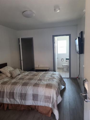 a bedroom with a bed and a television and a bathroom at Nights Inn Motel in Oakland
