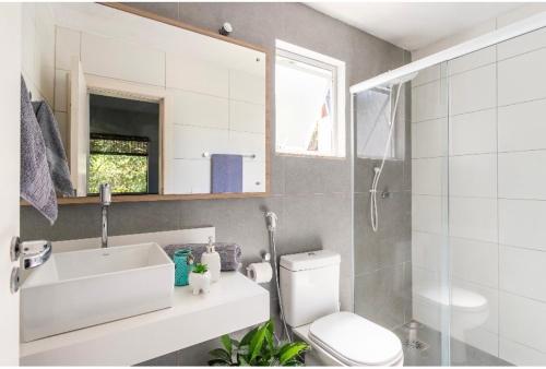 a bathroom with a toilet and a sink and a mirror at Guest room Casa SEA in Florianópolis