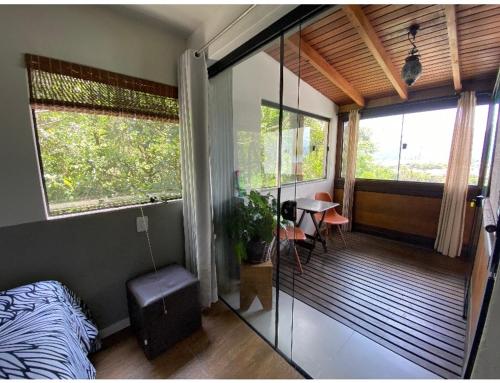 a bedroom with a bed and a balcony with windows at Guest room Casa SEA in Florianópolis