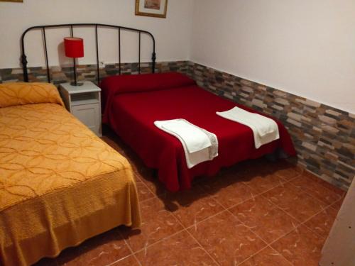1 dormitorio con 2 camas y colcha roja en Pensión Tabaza, en Carreno