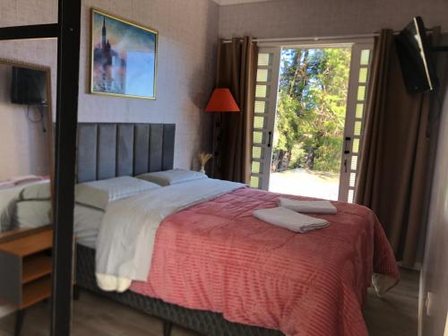 1 dormitorio con 1 cama grande con manta roja en Refúgio nas Nuvens en Campos do Jordão