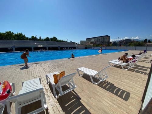 a group of people sitting on lounge chairs next to a swimming pool at Коттеджи Эко-Дэм in Sukhum