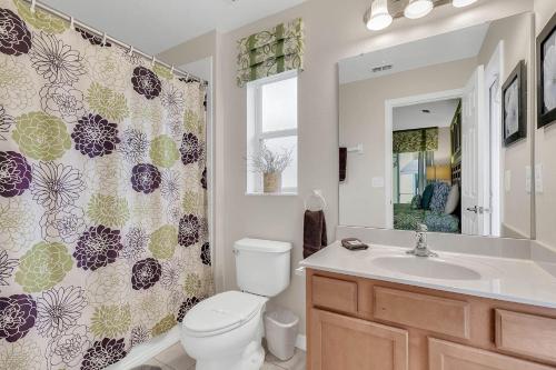a bathroom with a toilet and a sink and a shower curtain at 4 bedrooms pool home gated resort of Veranda Palms in Kissimmee