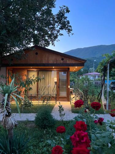 ein Haus mit einem Garten mit roten Blumen in der Unterkunft Qoqosa In Racha in Ambrolauri