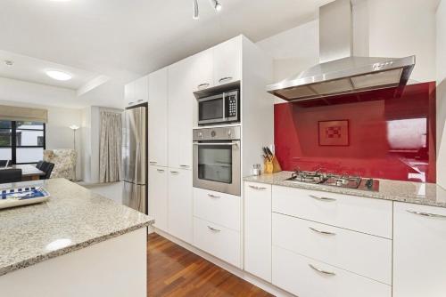 a kitchen with white cabinets and a red wall at The Glebe Apartments in Queenstown