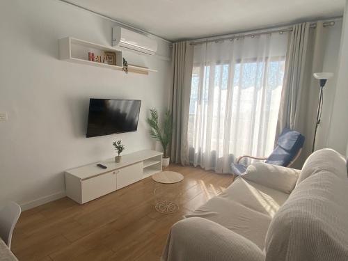 ein weißes Wohnzimmer mit einem Sofa und einem TV in der Unterkunft Torrenueva con vistas al mar in Torrenueva