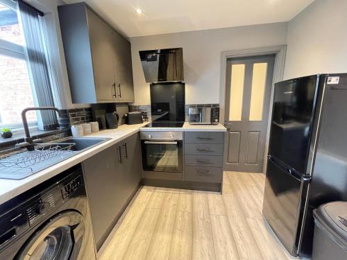 a kitchen with stainless steel appliances and a washer and dryer at Seaviews Apartment, Whitley Bay Sea Front in Whitley Bay