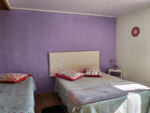 1 dormitorio con paredes moradas y 2 camas con almohadas en Residencia Cardoso, en Canela