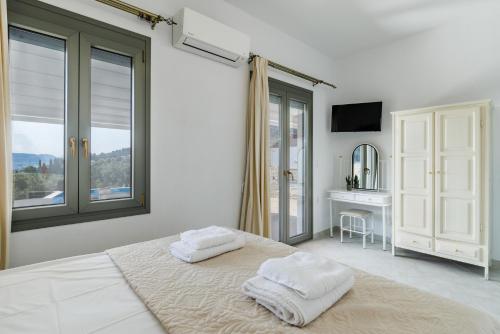 a white bedroom with two towels on a bed at Villa Ameli in Neo Klima