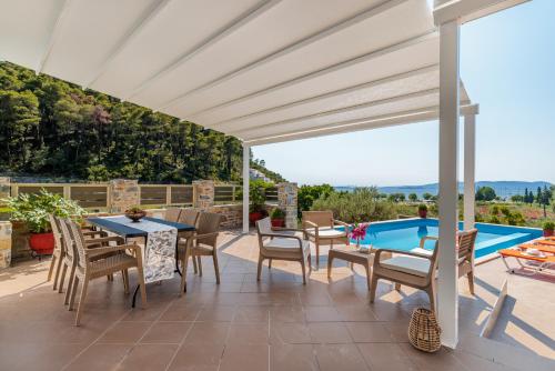 a patio with a table and chairs and a swimming pool at Villa Ameli in Neo Klima
