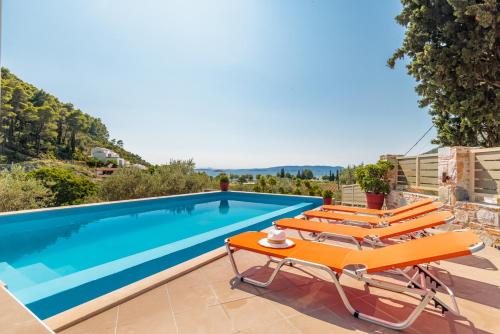 a villa with a swimming pool and lounge chairs at Villa Ameli in Neo Klima