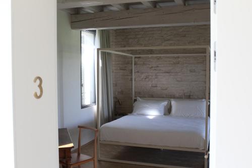 a bedroom with a canopy bed with a brick wall at Corte LOIOL in Scorzarolo