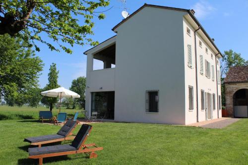 a couple of chairs sitting on the grass in front of a house at Corte LOIOL in Scorzarolo