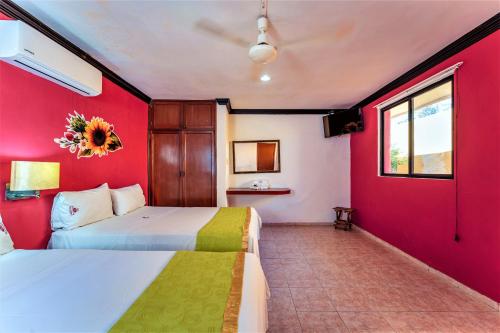 Habitación con 2 camas y pared roja. en Hotel Gran Centenario, en Mérida