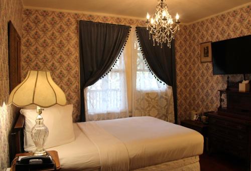 a bedroom with a bed with a lamp and a chandelier at Copper Queen Hotel in Bisbee
