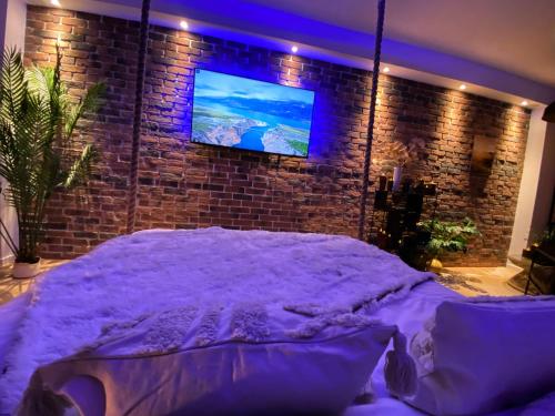 a bedroom with a purple bed with a tv on a brick wall at Saphir Spa in Amiens
