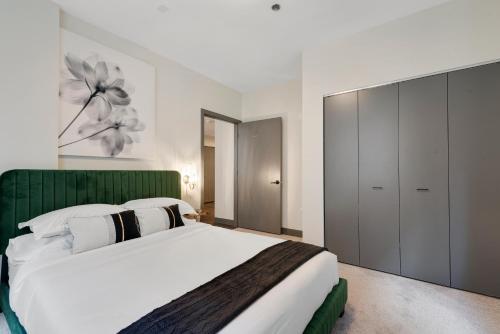 a bedroom with a large bed with a green headboard at Experience Downtown Chicago at Millennium - Luxury Apartments in The Loop in Chicago