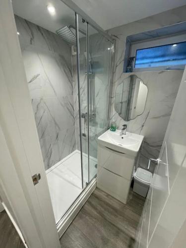 a white bathroom with a shower and a sink at Stylish & Cosy 1 Bed Apartment in Swindon