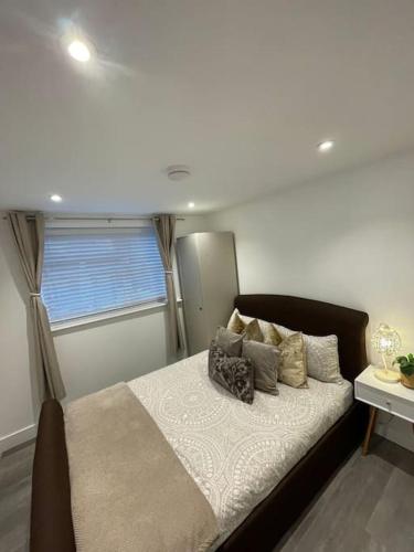 een slaapkamer met een bed met kussens en een raam bij Stylish & Cosy 1 Bed Apartment in Swindon