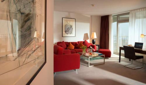 a living room with a red couch and a table at Dorint An der Kongresshalle Augsburg in Augsburg
