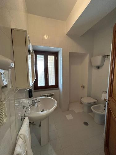 a white bathroom with a sink and a toilet at La Locanda del Convento in Tropea